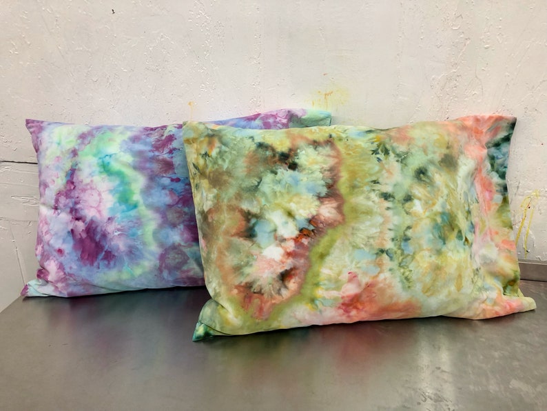 May include: Two tie-dye pillowcases, one in shades of purple, blue, and green, and the other in shades of green, yellow, and orange.