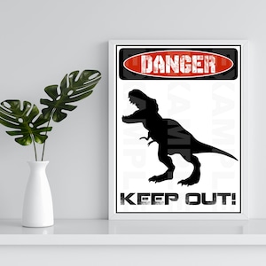 May include: A white sign with a red and black danger sign that says "DANGER" and a black silhouette of a Tyrannosaurus Rex dinosaur. The sign also says "KEEP OUT!"