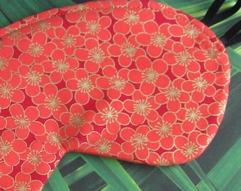 Könnte beinhalten: Rote Schlafmaske mit goldenem Blumenmuster. Die Maske ist aus Stoff und hat ein elastisches Band.