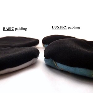 May include: Two close-up images of seat cushions with different padding. The left cushion is labeled "BASIC padding" and has a thin layer of black padding. The right cushion is labeled "LUXURY padding" and has a thicker layer of black padding with a blue and white patterned fabric underneath.