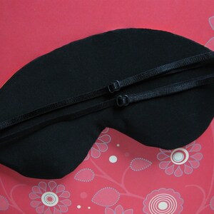 May include: Black sleep mask with adjustable straps. The mask is made of soft fabric and is designed to block out light.