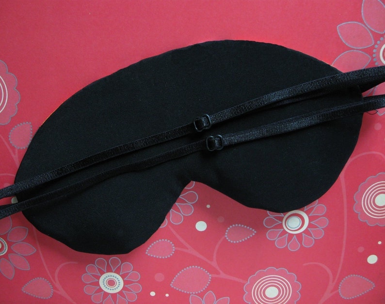 May include: Black sleep mask with adjustable straps. The mask is made of soft fabric and is designed to block out light.