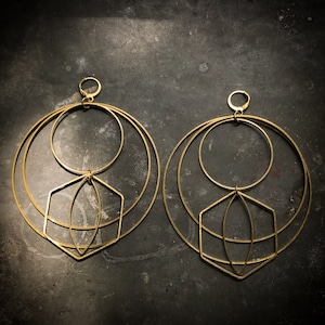 May include: A pair of gold geometric hoop earrings with multiple circles and a diamond shape in the center.