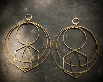 May include: A pair of gold geometric hoop earrings with multiple circles and a diamond shape in the center.