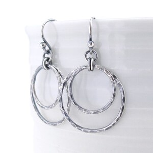 Puede incluir: Pendientes de plata martillados de doble c&iacute;rculo con acabado texturizado. Los pendientes tienen un dise&ntilde;o simple y minimalista.