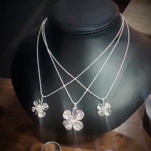 Pingente ou brincos de trevo de quatro folhas feitos de prata. Moedas americanas vintage: dez centavos, vinte e cinco centavos e cinquenta centavos.