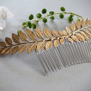 May include: Gold leaf hair comb with a silver comb on the bottom. The comb is shaped like a branch with leaves.