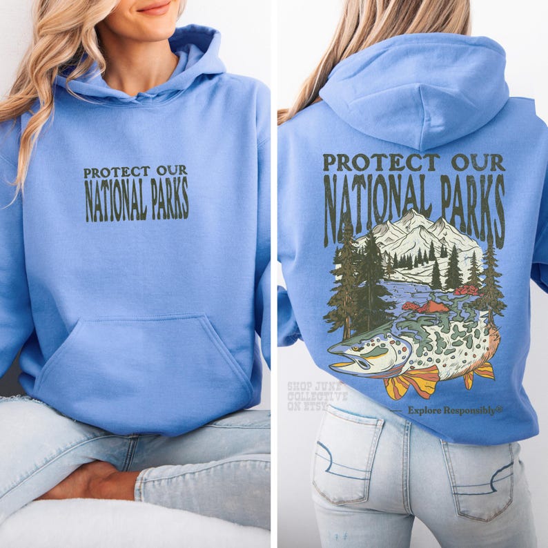 May include: A light blue hooded sweatshirt featuring the text "PROTECT OUR NATIONAL PARKS" on the front. The back displays the same text above a graphic illustration of a mountain range, pine trees, and a large fish with orange fins.