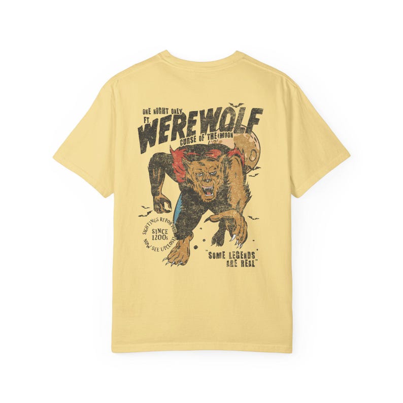 May include: A pale yellow short-sleeve t-shirt featuring a graphic on the back of a werewolf with the text "ONE NIGHT ONLY FT. WEREWOLF CURSE OF THE MOON", "SIGHTINGS REPORTED SINCE 1200 AD", "NOW SEE UPCLOSE", and "SOME LEGENDS ARE REAL".