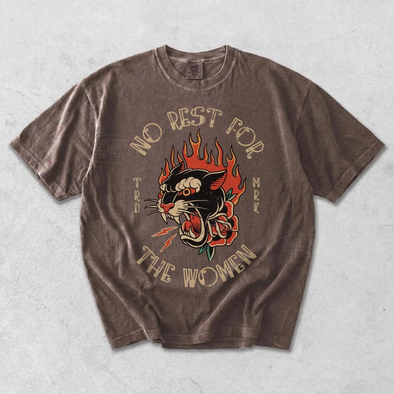 May include: Brown t-shirt featuring a black panther design with red flames and a rose. The text "NO REST FOR THE WOMEN" is arched above the panther. The shirt has a vintage, worn appearance.