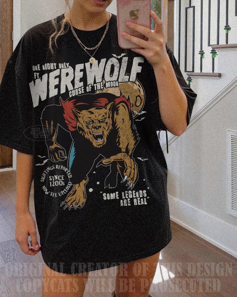 May include: A black short-sleeve t-shirt featuring a graphic of a werewolf with red and brown fur. The text reads: ONE NIGHT ONLY FT. WEREWOLF CURSE OF THE MOON, SIGHTINGS REPORTED SINCE 1200S NOW SEE UPCLOSE, and SOME LEGENDS ARE REAL.