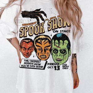 May include: A white t-shirt featuring a graphic print of three monster faces and a clawed hand. The text reads: Midnight Spook Show, Ft. Real Monsters, On Stage, The Creepiest Horror Show You've Ever Seen, Friday Oct. 13, One Night Only.