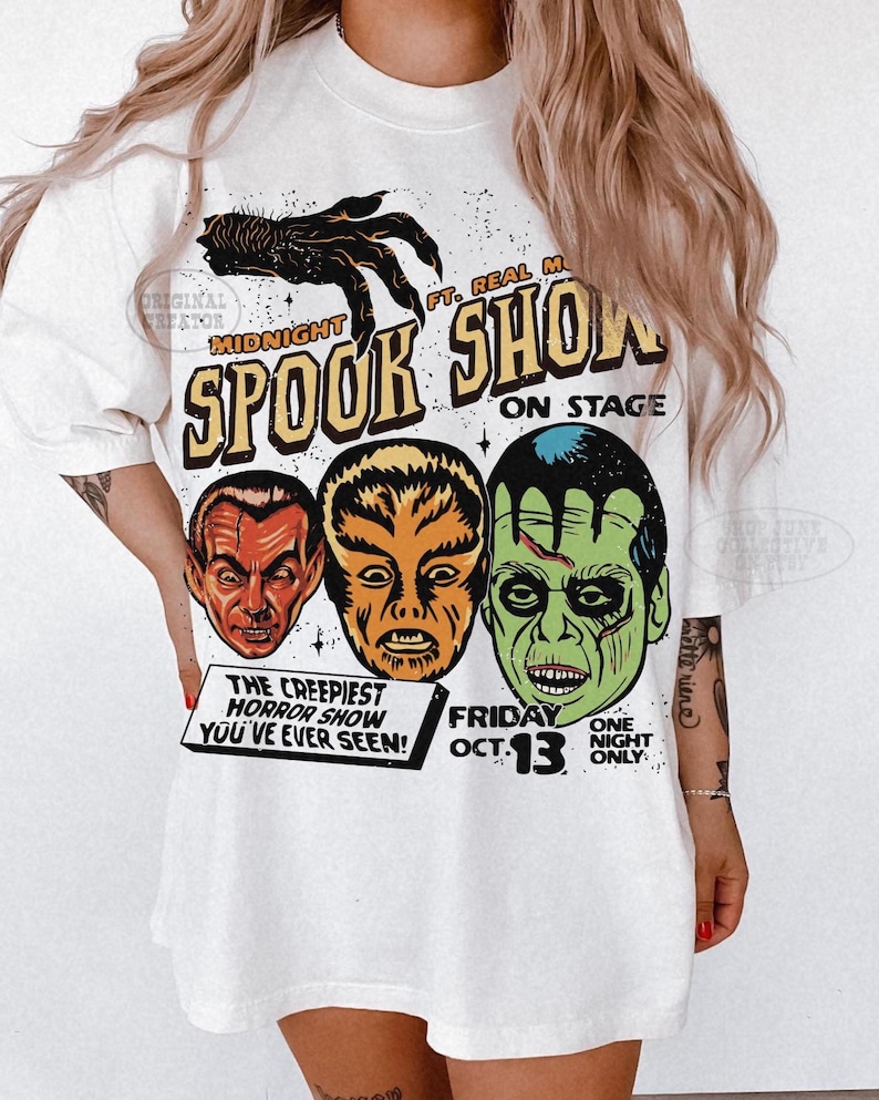 May include: A white t-shirt featuring a graphic print of three monster faces and a clawed hand. The text reads: Midnight Spook Show, Ft. Real Monsters, On Stage, The Creepiest Horror Show You've Ever Seen, Friday Oct. 13, One Night Only.