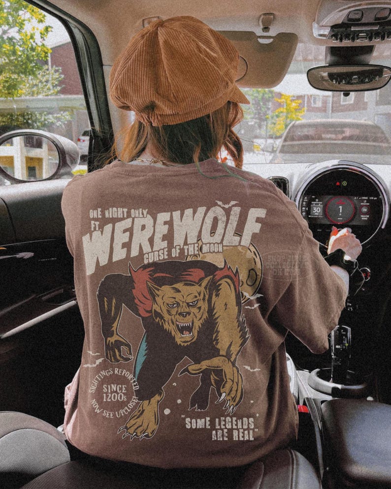 May include: A brown t-shirt featuring a graphic print of a werewolf with the text "ONE NIGHT ONLY FT. WEREWOLF CURSE OF THE MOON" and "SOME LEGENDS ARE REAL" along with "SIGHTINGS REPORTED SINCE 1200S NOW SEE UPCLOSE". The shirt is worn with a brown corduroy cap.
