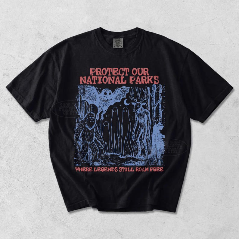 Peut inclure: Un t-shirt noir &agrave; manches courtes avec une impression graphique bleue repr&eacute;sentant une sc&egrave;ne de for&ecirc;t avec un hibou, un sasquatch, des fant&ocirc;mes et une cr&eacute;ature ressemblant &agrave; un cerf. Le texte indique PROTECT OUR NATIONAL PARKS et WHERE LEGENDS STILL ROAM FREE.