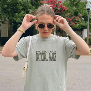 May include: A light green t-shirt with the text "PROTECT OUR NATIONAL PARKS" printed in dark green on the front.