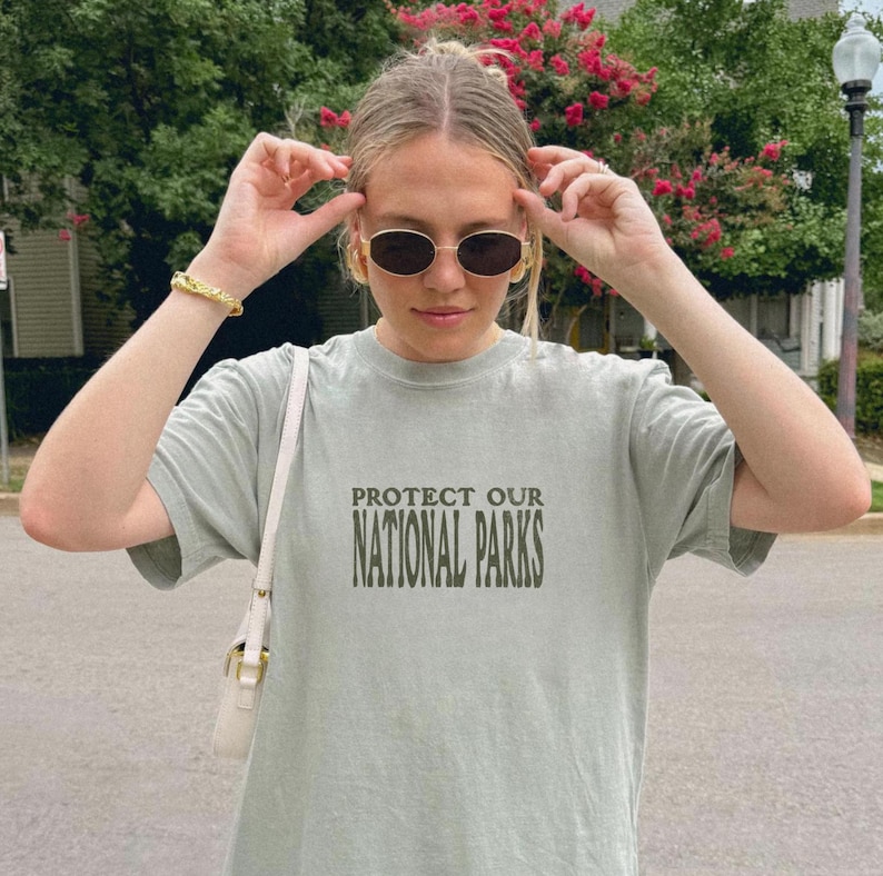 May include: A light green t-shirt with the text "PROTECT OUR NATIONAL PARKS" printed in dark green on the front.