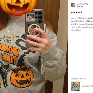 Peut inclure: Un sweat-shirt gris chin&eacute; &agrave; col rond avec un chat noir, une citrouille d'Halloween portant un chapeau de sorci&egrave;re et le texte orange et noir "IT'S THE MOST WONDERFUL TIME OF THE YEAR" imprim&eacute; sur le devant. Le motif inclut de petites &eacute;toiles orange.