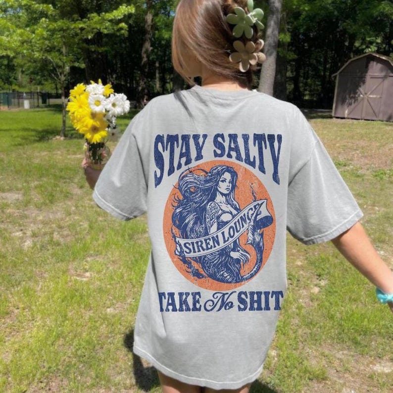 May include: Gray t-shirt with a graphic of a mermaid with the text "Stay Salty Siren Lounge Take No Shit" printed on the back.