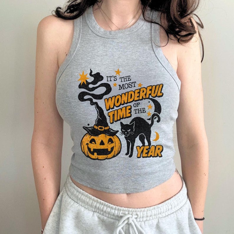 May include: Gray tank top with a Halloween-themed graphic. The design includes a jack-o'-lantern wearing a witch hat, a black cat, and the text "It's the most wonderful time of the year" in orange and yellow.
