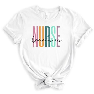 May include: White t-shirt with the text "NURSE forensics" in colorful vertical letters. The letters are pink, orange, teal, and purple.