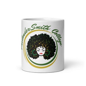 May include: White ceramic mug with a green and gold circle design featuring a black woman with an afro and the text "Thelander Smith College".