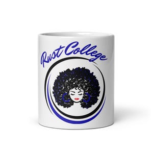 May include: White ceramic mug with a blue and black design. The design features a woman with an afro and the text "Rust College".