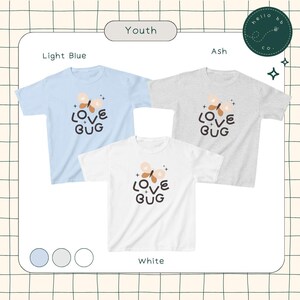 May include: Three youth t-shirts in light blue, ash grey, and white with a butterfly graphic and the text "LOVE BUG" printed on the front.