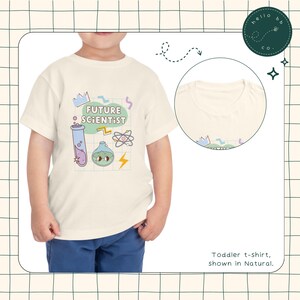 May include: A natural-colored toddler t-shirt featuring a colorful graphic with the words "FUTURE SCIENTIST". The design includes a crown, test tube, atom, and a cartoon flask with a face. The shirt is shown in natural color.