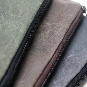 May include: Three zippered pouches made of waxed canvas in shades of green, brown, and gray.