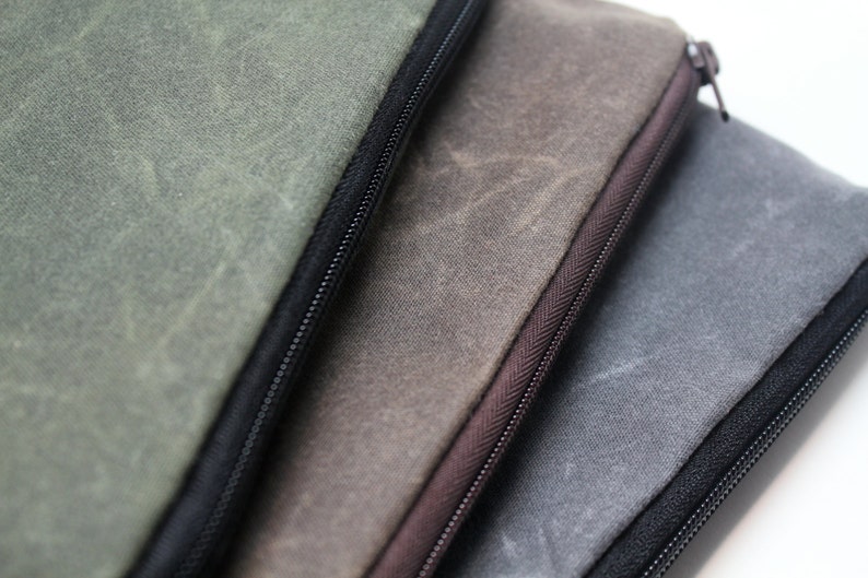 May include: Three zippered pouches made of waxed canvas in shades of green, brown, and gray.