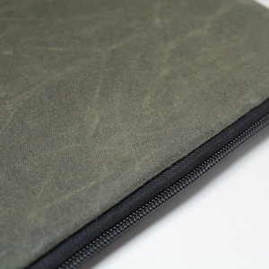 May include: A green canvas zippered pouch with a black zipper. The pouch is made of a durable, water-resistant material.