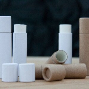 May include: A set of six white and brown cardboard tubes, some with lids. The tubes are various sizes and are arranged on a wooden surface.