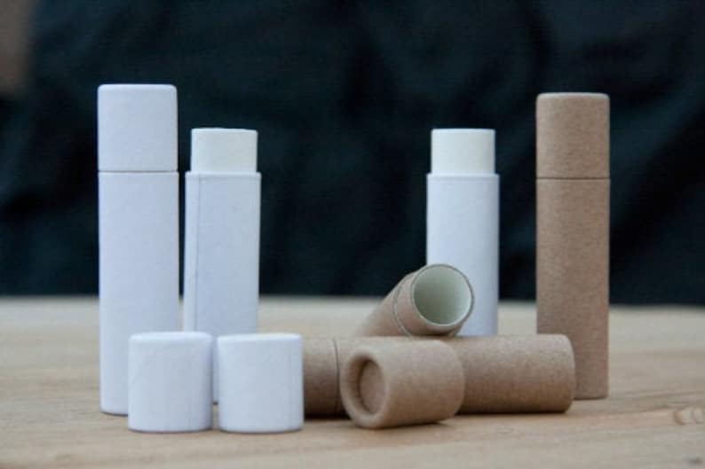 May include: A set of six white and brown cardboard tubes, some with lids. The tubes are various sizes and are arranged on a wooden surface.