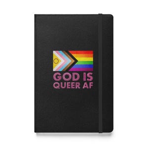 May include: Black notebook with a rainbow flag design and the text "GOD IS QUEER AF" in pink glitter lettering. The notebook has a black elastic band closure.