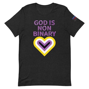 Puede incluir: Una camiseta negra con el texto "God is Non Binary" en letras moradas. Un símbolo de corazón morado, amarillo y blanco está centrado debajo del texto. El texto "JUNETEENTH FOR ALL" está impreso en blanco sobre un pequeño rectángulo morado en la esquina superior derecha de la camiseta.