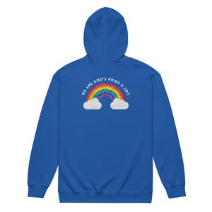 Puede incluir: Una sudadera con capucha azul real con un diseño de arcoíris y nubes. El arcoíris es multicolor y está arqueado sobre dos nubes blancas. El texto "WE ARE GOD'S PRIDE & JOY" está encima del arcoíris en semicírculo.
