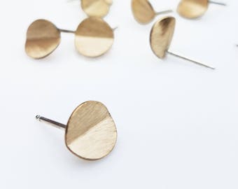 Puede incluir: Un par de pendientes de color dorado con un diseño de medio círculo. Los pendientes están hechos de metal y tienen un estilo simple y moderno.