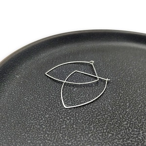 May include: A pair of silver hoop earrings with a unique, asymmetrical, teardrop shape.