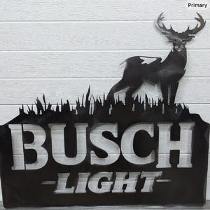 May include: Black metal sign featuring a deer silhouette above the words "BUSCH LIGHT". The sign has a cutout design with the text and deer against a white wooden background. The deer has large antlers.