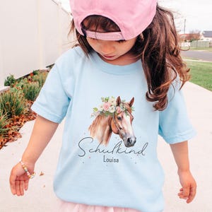 Personalisiertes Einschulungs T-Shirt 2026 mit Name für Mädchen, Schulkind Shirt mit Pferde-Motiv in Rosa Weiß und Blau, Einschulungsgeschenk für Pferdemädchen personalisiert mit Wunschname zum Schulstart