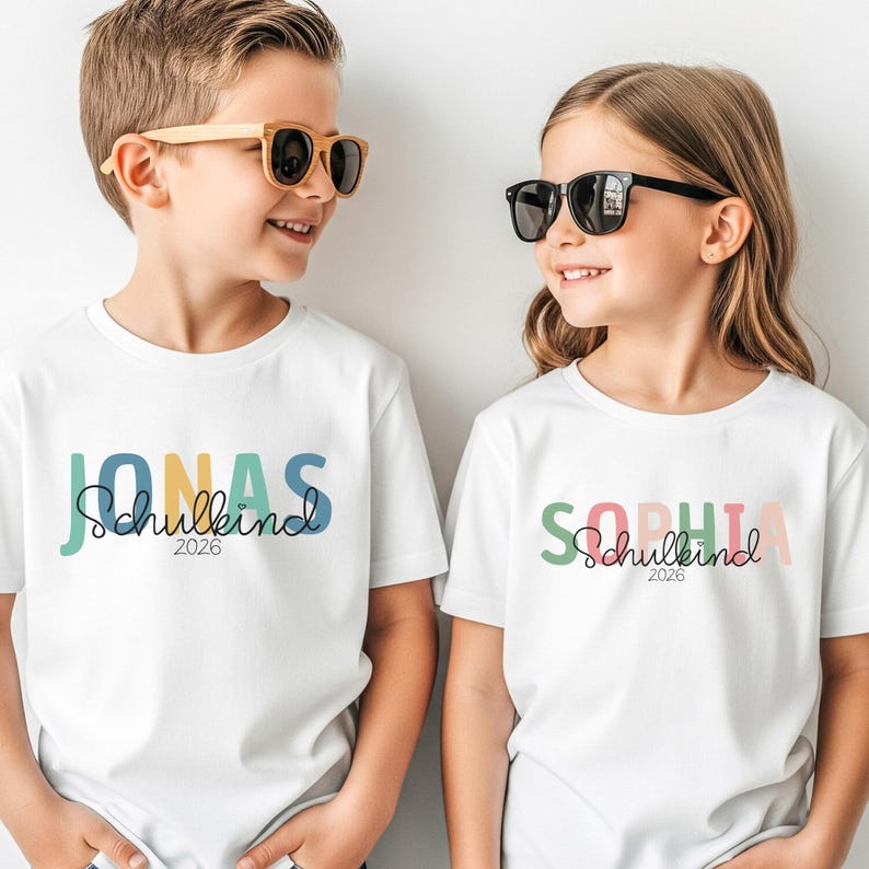 Einschulung T-Shirt 2026 personalisiert mit Name, Schulkind Shirt Mädchen, Tshirt zum Schulstart Junge, Einschulungsshirt Weiß Regenbogen