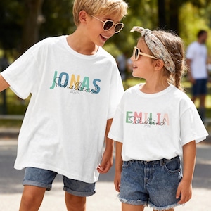 Einschulung T-Shirt 2026 personalisiert mit Name, Schulkind Shirt Mädchen, Tshirt zum Schulstart Junge, Einschulungsshirt Weiß Regenbogen