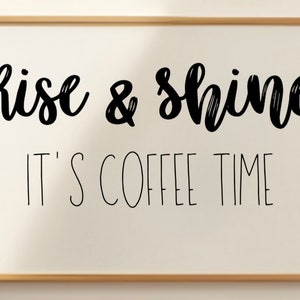 Könnte beinhalten: Ein weißes Schild in einem Rahmen mit schwarzem Text, auf dem "Rise & Shine It's Coffee Time" steht.