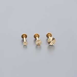 K&ouml;nnte beinhalten: Drei goldfarbene Ohrringe mit flacher R&uuml;ckseite und Sonnenstrahl-Design. Die Ohrringe sind in verschiedenen Gr&ouml;&szlig;en erh&auml;ltlich, mit einer kleinen, mittleren und gro&szlig;en Option. Die Ohrringe befinden sich auf einem grauen Hintergrund.