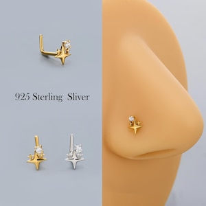 May include: A gold-colored nose ring with a star design and a small, clear gemstone. The nose ring is shown in multiple views, including one on a person's nose. The text "925 Sterling Sliver" is also visible.