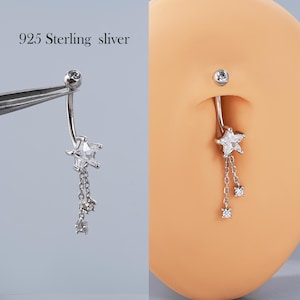 May include: A silver belly button ring with a star design and dangling chain with small, clear gems. The text "925 Sterling sliver" is visible in the image.