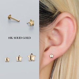 May include: Gold star-shaped earrings in various sizes, including a stud worn on an ear. The image also shows a flat-backed earring post and the text "14K SOLID GOLD".