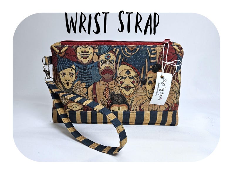 May include: A rectangular wrist strap bag with a zipper closure and a wrist strap. The bag features a print of vintage clowns in various expressions. The wrist strap is black and gold striped. The text "WRIST STRAP" is above the bag.