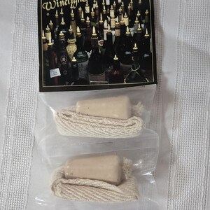 Op de afbeelding: Twee "Winelight" wijnfleslichtkits. Elke kit bevat een beige stop met een crèmekleurig touw. De verpakking bevat een afbeelding van verlichte wijnflessen.